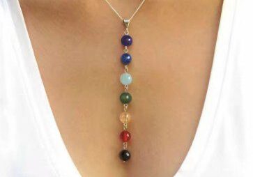 A woman wearing a necklace with seven different colored stones.