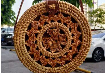 A round straw bag hanging on the side of a street.