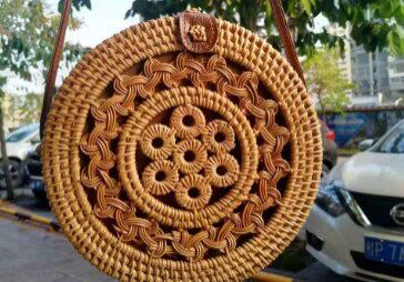 A round wicker bag hanging on the side of a street.