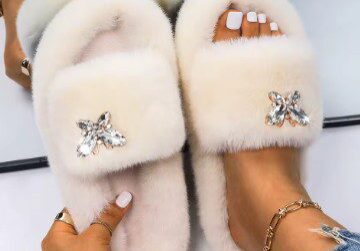 A person wearing white slippers with fur and star decorations.
