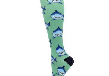 A person wearing green socks with blue sharks on them.