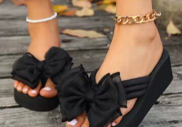 A woman wearing black sandals with bows on them.