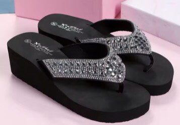 A pair of black flip flops with silver rhinestones.