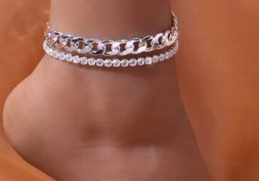 A woman wearing two silver anklets on her ankles.