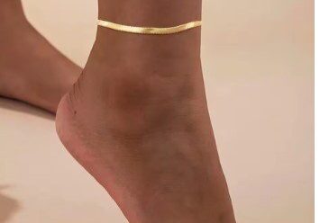 A woman wearing gold anklet on her ankle.