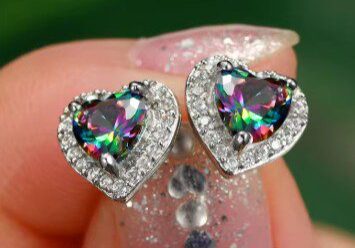 A woman holding onto some rainbow colored earrings