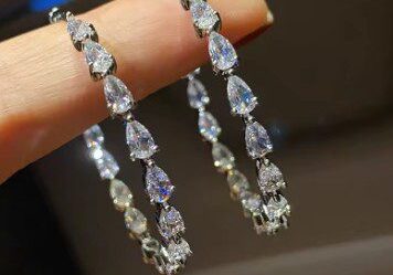 A hand holding two pairs of earrings.