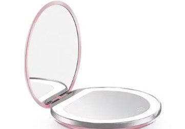 A pink compact mirror with light on top of it.