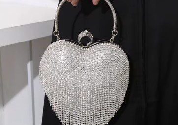 A woman holding onto a silver heart shaped purse