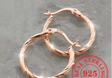 A pair of rose gold earrings on top of a table.