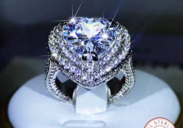 A diamond ring is sitting on top of a white stand.