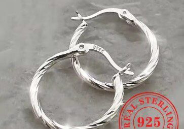 A pair of silver earrings sitting on top of a table.