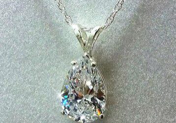 A diamond necklace is shown on the white surface.