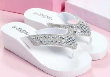 A pair of white flip flops with silver straps.